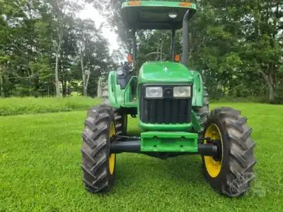 Green John Deere 5425 tractor with large tires and cab on grassy field.