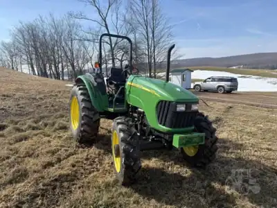 Green John Deere tractor with yellow wheels on grassy field during daytime.