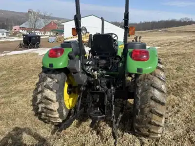 John Deere 2020 tractor with green body and large rear tires on a farm field.