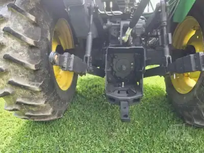 Front view of a green John Deere tractor with large rear tires and visible hydraulic components.