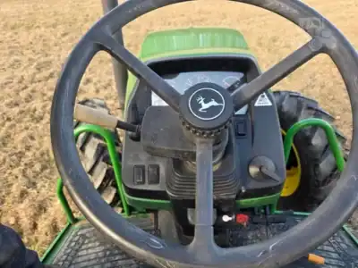 John Deere tractor, green and black, with steering wheel and control panel, on a field.