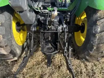 Heavy-duty green tractor with large yellow wheels and front hitch attachment for farming tasks.