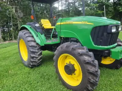 2007 John Deere 5425 tractor with green body and yellow wheels on grassy field.