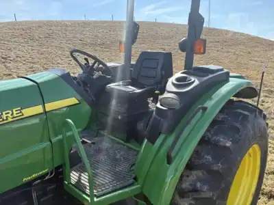Green John Deere 2020 tractor with black seat and large rear tires on a farm field.
