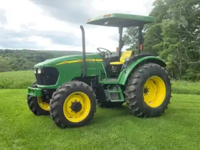 2007 John Deere 5425 tractor with cab and large rear tires on grassy field.