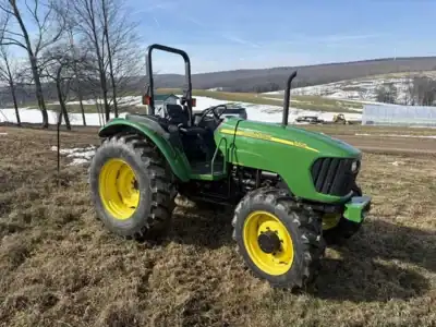 John Deere 5055E tractor with front loader, green and yellow, outdoor farm setting, no additional equipment visible.