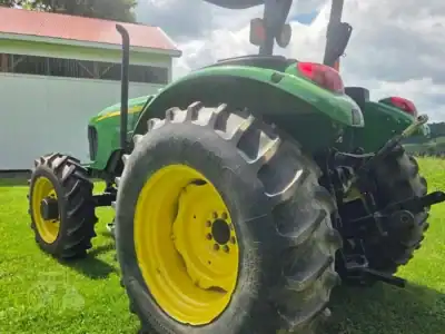 Green John Deere 5425 tractor with large rear tires and enclosed cab on grassy field.
