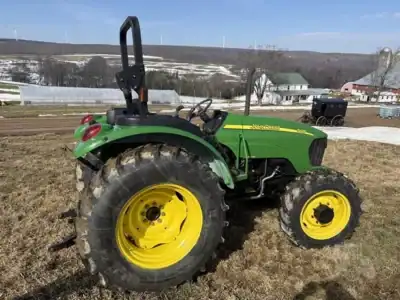Green John Deere 2020 tractor with large rear tires and a roll-over protection structure.