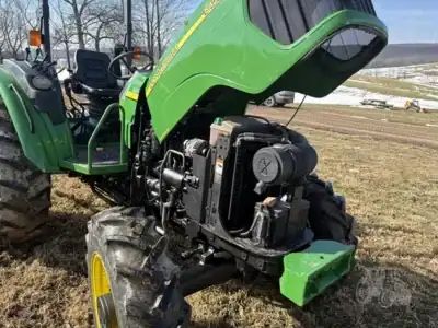 Green John Deere tractor with open hood showing engine, outdoor field setting, no visible year or model.
