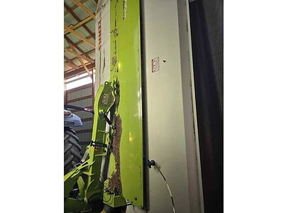 John Deere 7400 self-propelled sprayer in a warehouse, green and white equipment for agricultural spraying.
