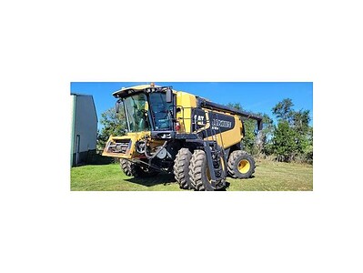 John Deere 772GP self-propelled sprayer with large tires and yellow and black body, parked on grass under clear blue sky.