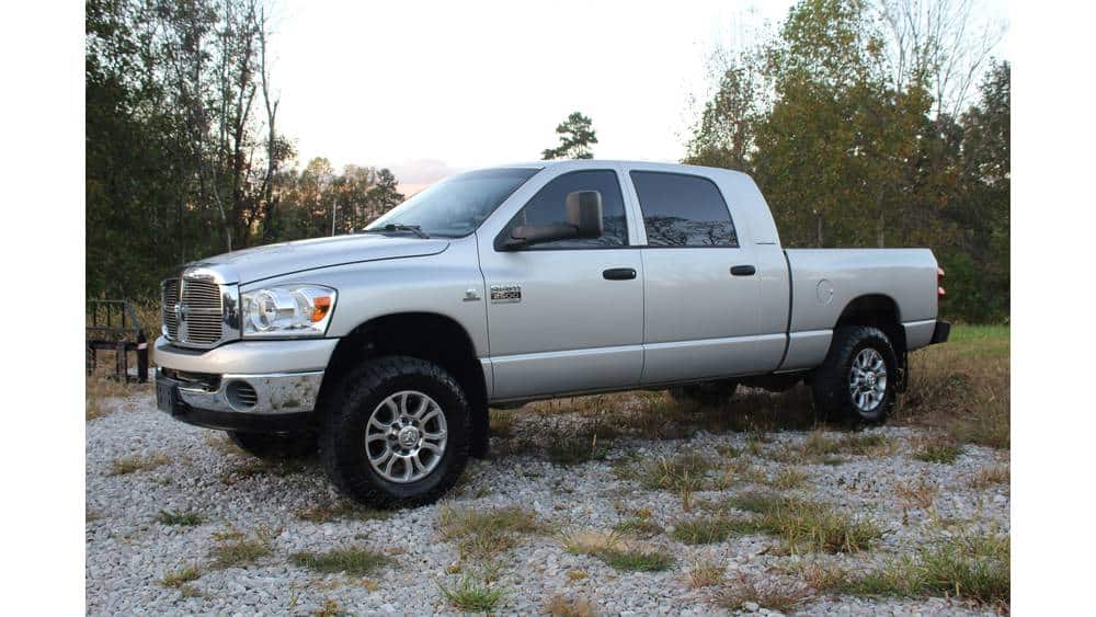 Dodge Ram 2500 4x4 pickup truck parked outdoors on gravel with trees in the background.