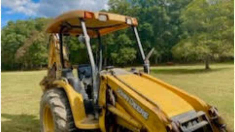 Yellow John Deere tractor with front loader attachment in a grassy field.