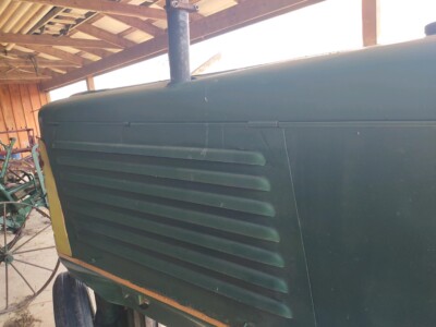 Oliver 77 tractor with green body and yellow accents, under a wooden shed.