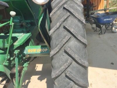 Oliver 77 tractor with large rear tire and green body, parked under a shed.