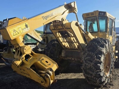 Caterpillar Tigercat forestry loader with large tracks and cab under clear blue sky.