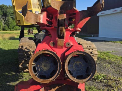 Red forestry mulcher attachment for skid steer loader with cutting teeth and drum.