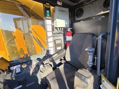 Interior of a yellow construction vehicle with control panel and seat.