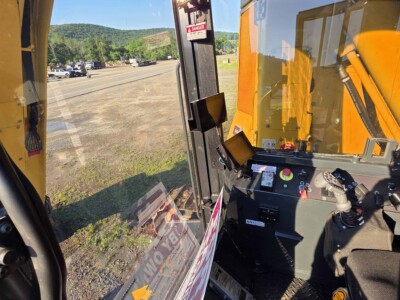 Interior view of a yellow construction vehicle with control panel and steering wheel.