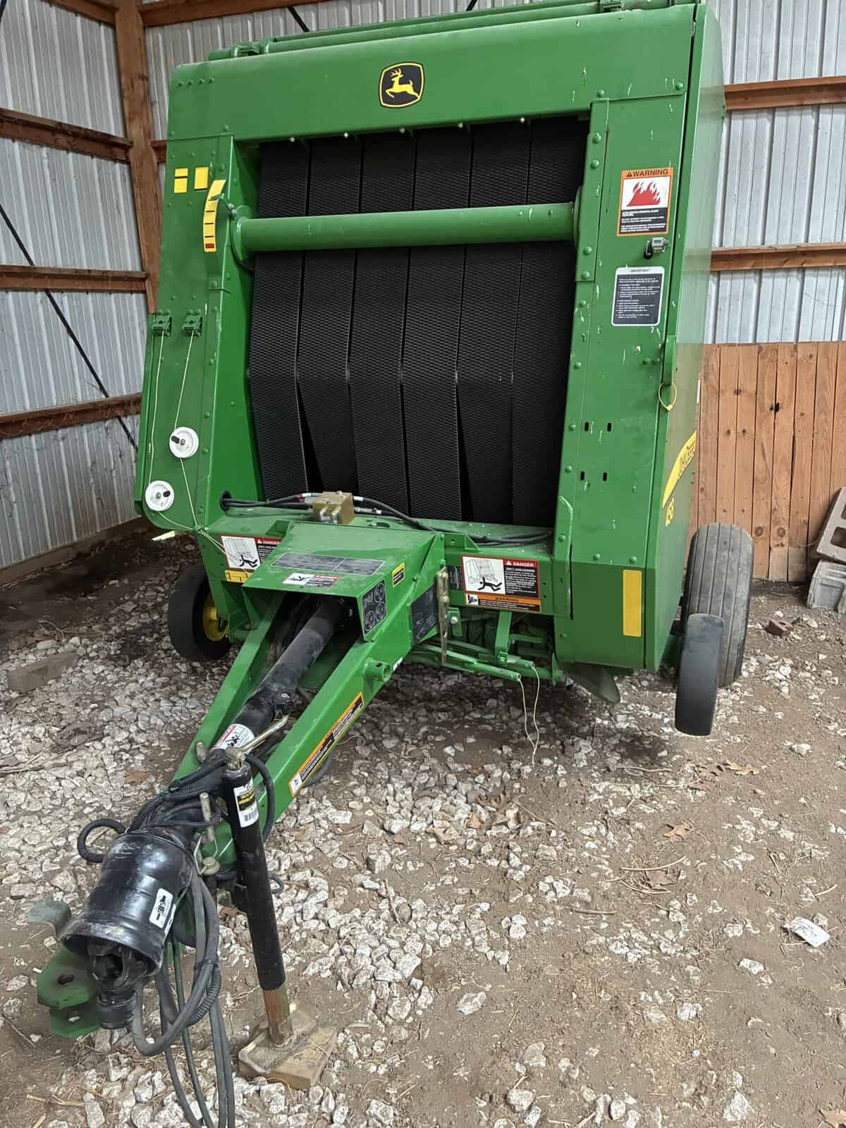 John Deere 458 Round Baler for Hay John Deere 458 round baler with black chamber and green exterior in storage.