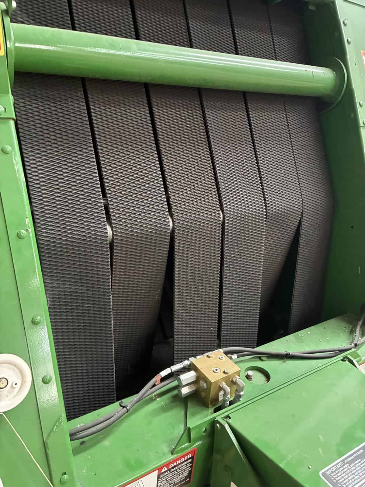 John Deere 458 Harvester Header Close-up of John Deere 458 combine harvester header with black rubber fingers and green frame.