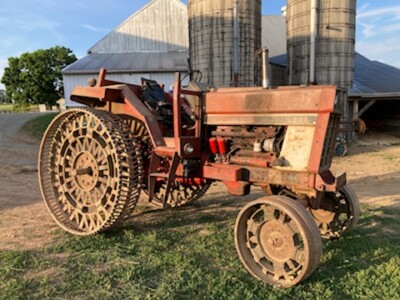 Farmall 300 tractor with steel wheels and rusted orange paint, vintage farm equipment from the 1950s.