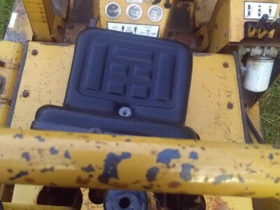 Operator controls and dashboard of a yellow Caterpillar compact loader with wear and tear visible.