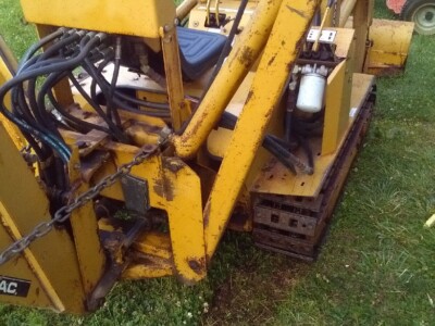 Yellow track loader with hydraulic system and operator seat, used for construction or landscaping.