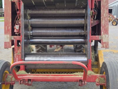 Red agricultural equipment with rollers and a black top, used for processing crops or materials.