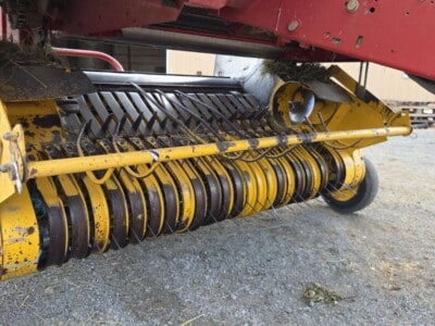Close-up of New Holland 648 rotary cutter with yellow and black blades and protective cover.