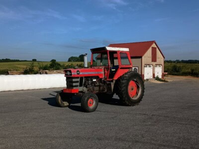 Red Massey Ferguson 1130 tractor with cab and large rear tires on asphalt.