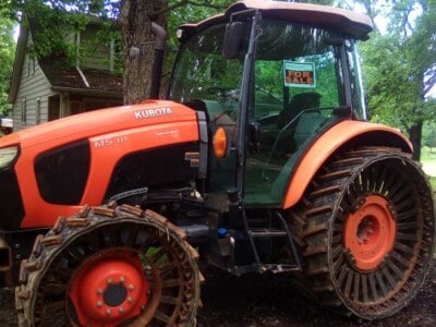 2018 Kubota M5-111 tractor with rubber tracks and enclosed cab in outdoor setting.