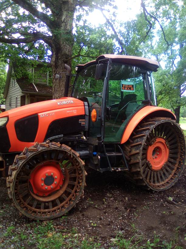 2018 Kubota M5-111 tractor with rubber tracks and enclosed cab in outdoor setting.