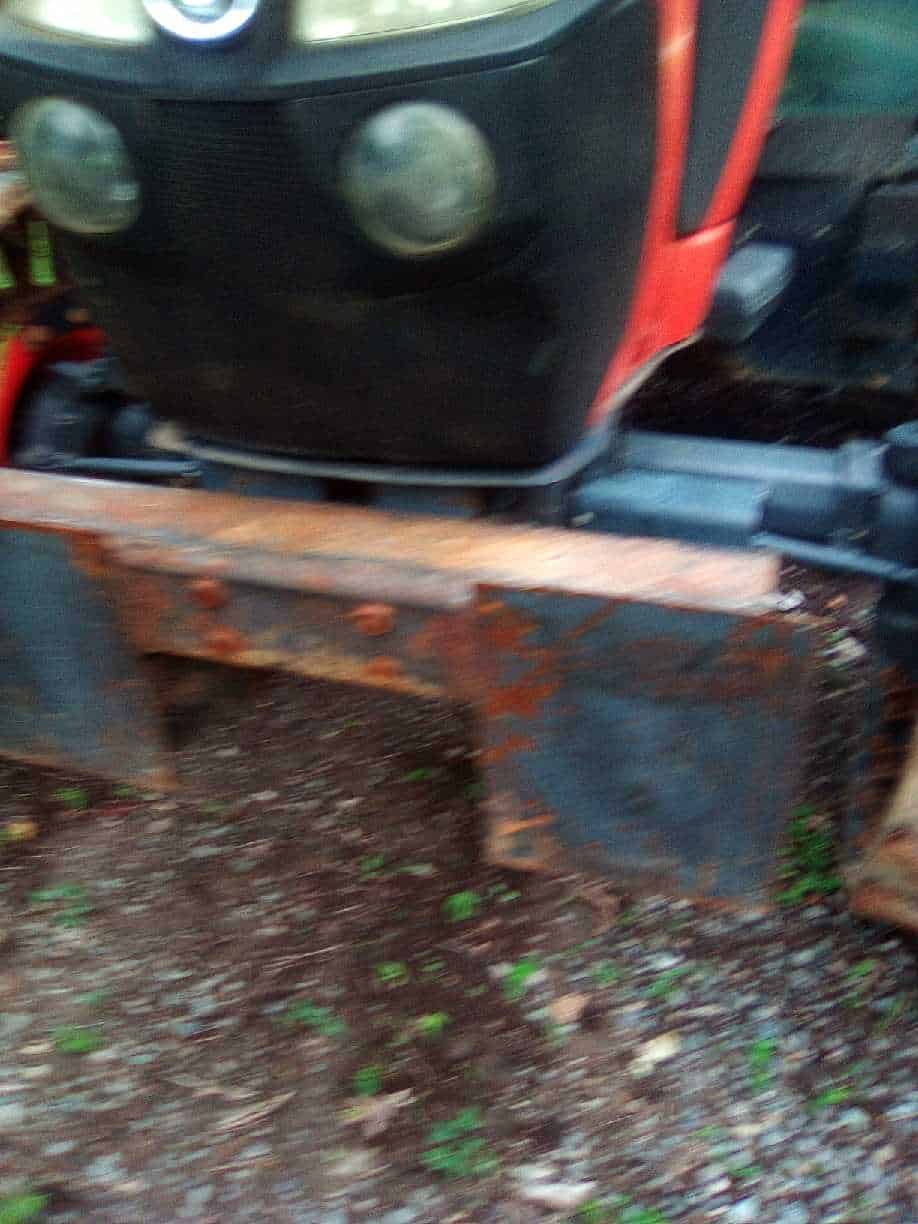 image000006 (1) Red tractor with front blade attachment and black cab, showing signs of rust and wear.