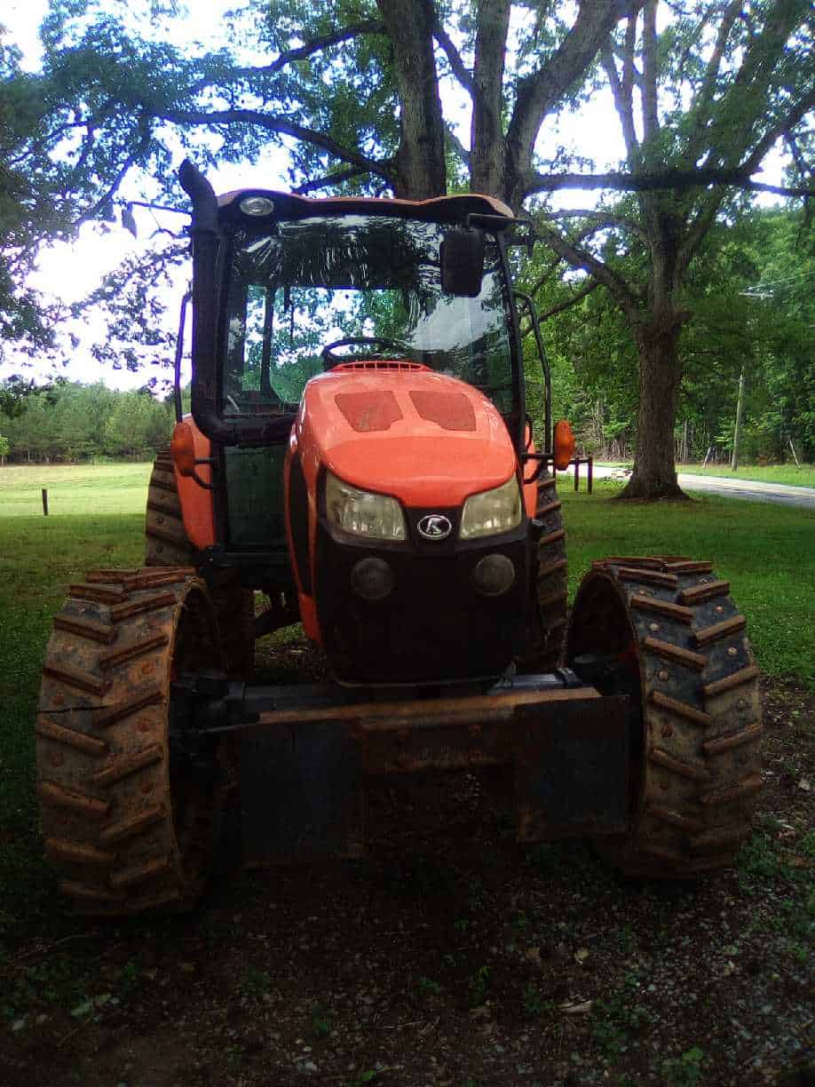 image000007 (1) 2018 Kubota M5-111 tractor with enclosed cab and large tracked tires in a grassy area.