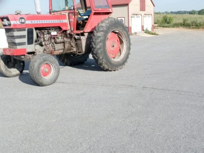Red Massey Ferguson 1130 tractor with enclosed cab and large rear tires on asphalt surface.