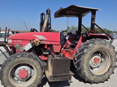 Red McCormick C70 tractor with canopy and large tires on a farm lot.