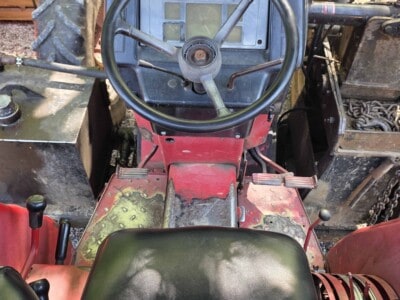 Close-up of McCormick C70 tractor dashboard and steering wheel with seat in foreground.