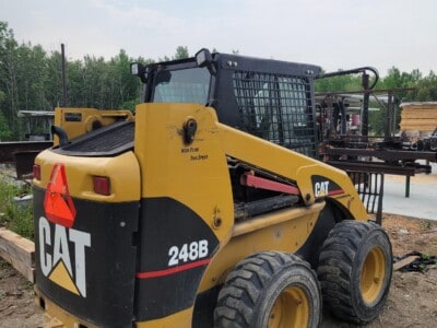 Caterpillar 248B skid steer loader with enclosed cab and large tires, outdoor setting.