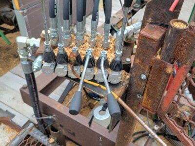 Hydraulic control valve assembly with multiple hoses and levers for machinery operation.