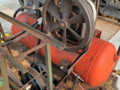 Old industrial engine with large flywheel and belt drive for sawmill operations.