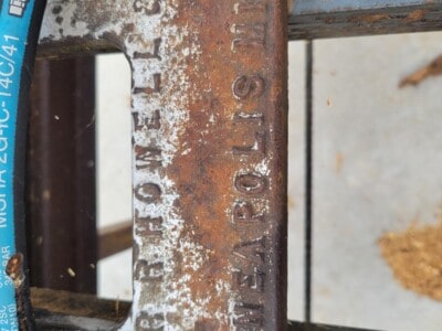 Close-up of a rusted metal identification plate on machinery with embossed text.