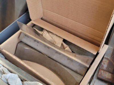 Metal cutting blade inside cardboard box with protective paper, used for industrial cutting tasks.