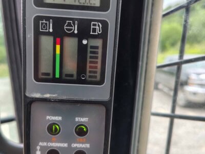 Close-up of a construction equipment control panel with digital display and gauges.
