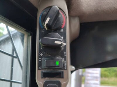 Cab climate control panel with temperature and fan speed dials, and a green power indicator light.