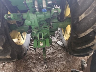 Rear view of a 2010 John Deere 6100D tractor showing large tires and hydraulic connections.