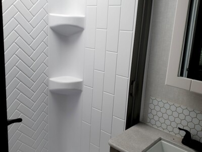 Contemporary bathroom with white tiled shower and gray vanity with sink.