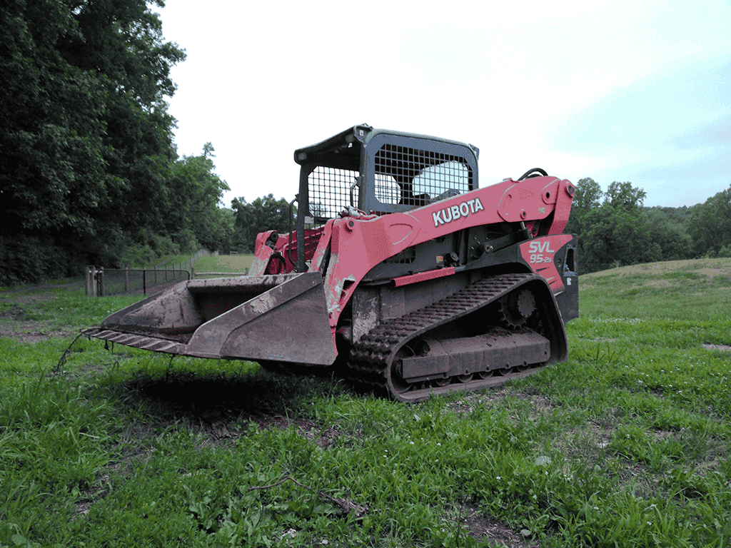 2018 Kubota SVL95-2 compact track loader with enclosed cab and bucket attachment on grassy field.
