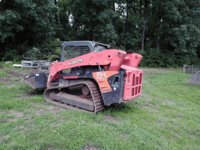2018 Kubota SVL95-2 compact track loader with enclosed cab and rubber tracks on grassy field.