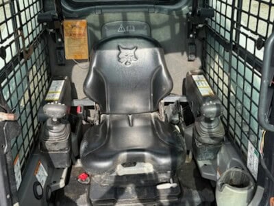 Interior view of a 2018 Bobcat T650 compact track loader with enclosed cab and control levers.